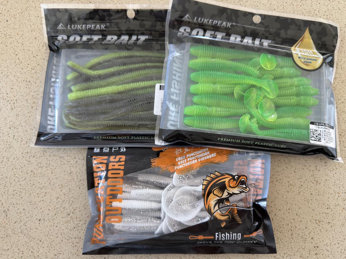 Three packs of soft plastic baits - straight worm, curly tail grub, paddle tail